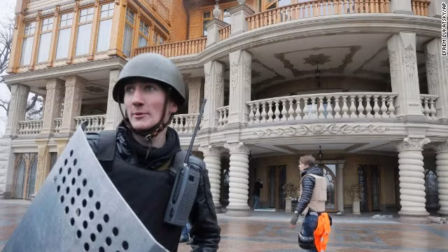 Một người biểu tình canh gác tư dinh xa hoa của ông Yanukovych ở ngoại ô Kiev hôm 22/2. Các nhân viên an ninh và tình nguyện viên cũng kéo tới đây để bảo vệ tư dinh này khỏi bị cướp bóc và phá hoại.