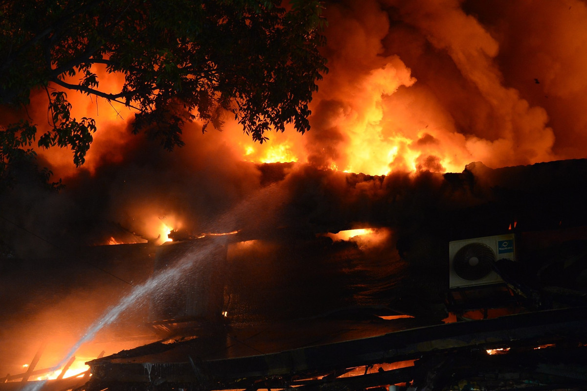 Dùng vòi rồng phun nước dập lửa từ mặt tiền và hông quán.