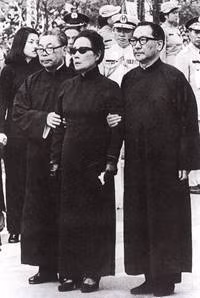 Chi tiết này cần phải giải thích thêm rằng, vào năm 1927, khi chính thức kết hôn với Tống Mỹ Linh, họ Tưởng đã từ bỏ đạo Phật và theo đạo Cơ đốc, vì vậy, trong đám tang của ông ta có sự xuất hiện của 5 cây thánh giá như đã miêu tả. Ảnh: Tống Mỹ Linh được Tưởng Kinh Quốc, Tưởng Vĩ Quốc dìu hai bên trong đám tang Tưởng Giới Thạch.