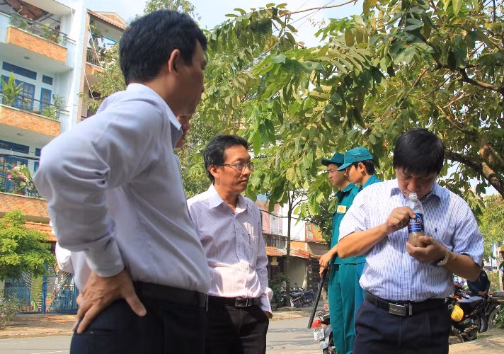 Giám đốc Sở KHCN Phan Minh Tân (người cầm chai nước) kiểm tra mẫu nước thu tại hố phát nổ và cháy