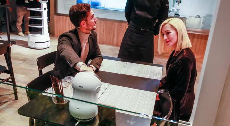 Nhân viên giải thích cho khách cách họ có thể tương tác với robot trên bàn.