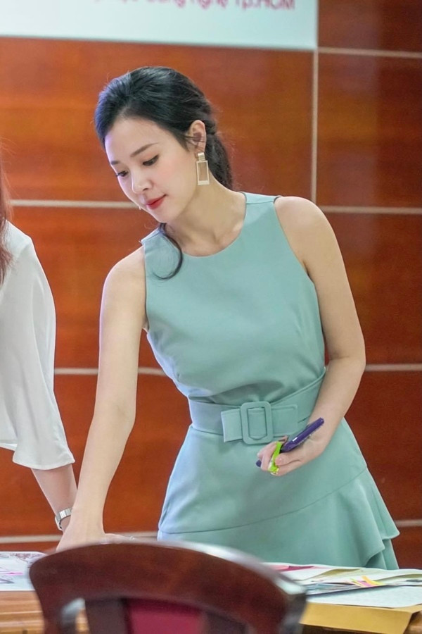 Mẫu đầm chữ A đơn sắc, tối giản quen thuộc mỗi khi cô đứng lớp hay chấm thi. Những đường cắt tinh giản cùng chi tiết thắt lưng bản chữ nhật đồng màu khéo tôn vóc dáng mảnh mai, vòng eo thon gọn. Hài hòa cùng nước da trắng, xanh ngọc - tông màu Midu ưa chuộng - là lựa chọn trang phục hàng đầu cho các sự kiện và cuộc gặp quan trọng.