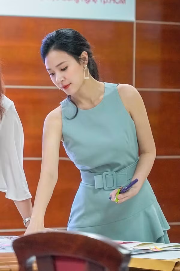 Mẫu đầm chữ A đơn sắc, tối giản quen thuộc mỗi khi cô đứng lớp hay chấm thi. Những đường cắt tinh giản cùng chi tiết thắt lưng bản chữ nhật đồng màu khéo tôn vóc dáng mảnh mai, vòng eo thon gọn. Hài hòa cùng nước da trắng, xanh ngọc - tông màu Midu ưa chuộng - là lựa chọn trang phục hàng đầu cho các sự kiện và cuộc gặp quan trọng.