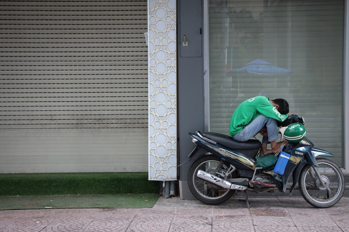 Mặt bằng trống trở thành nơi nghỉ ngơi của tài xế. Các shipper đợi nổ đơn giao đồ ăn từ số ít hàng quán còn kinh doanh.