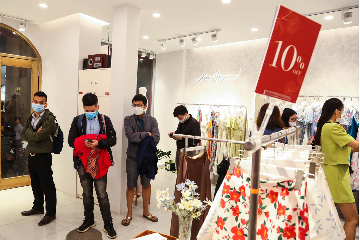 Tại một cửa hàng trên đường Cầu Giấy, nhiều người đứng chờ bạn đi cùng lựa mua đồ giảm giá ở lối ra vào.