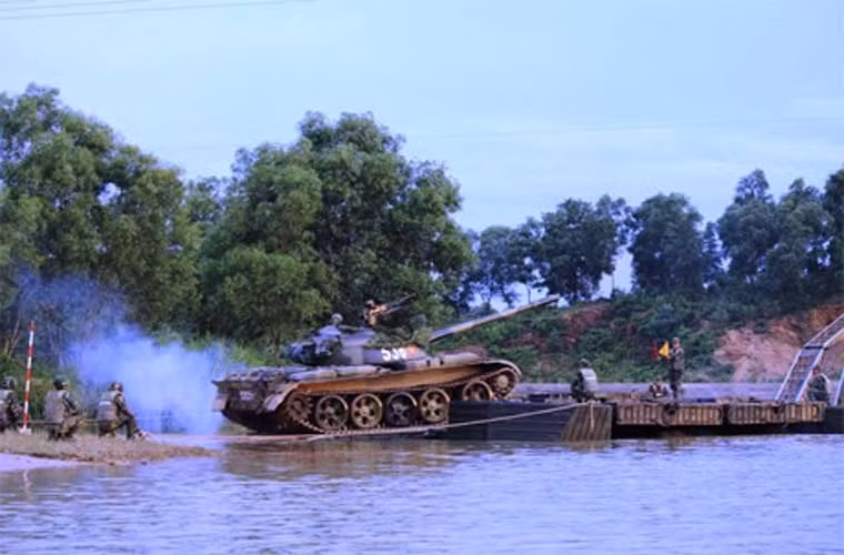 Xe tăng T-54 của Lữ đoàn 202 lăn bánh lên phà tự hành trong cuộc diễn tập vượt sông tại thao trường Sư đoàn 390. Điều đặc biệt là chiếc T-54 đã được sơn màu ngụy trang kiểu camo (xen kẽ các màu).