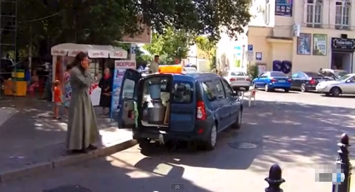 Trong khi đang xách đồ lên xe ô tô, người phụ nữ tranh thủ nói chuyện điện thoại. Bức ảnh chụp tại một góc phố trung tâm.