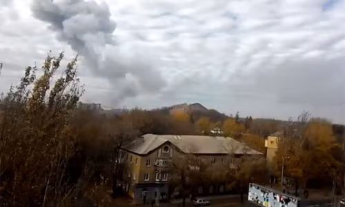 Một người dân địa phương quay hình ảnh ngọn khói đen cao vút bốc lên từ khu vực nhà máy bị trúng pháo kích.