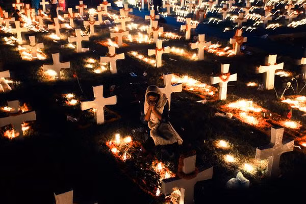 Một phụ nữ cầu nguyện tại một nghĩa trang được thắp sáng ánh vàng ở Dhaka, Bangladesh.