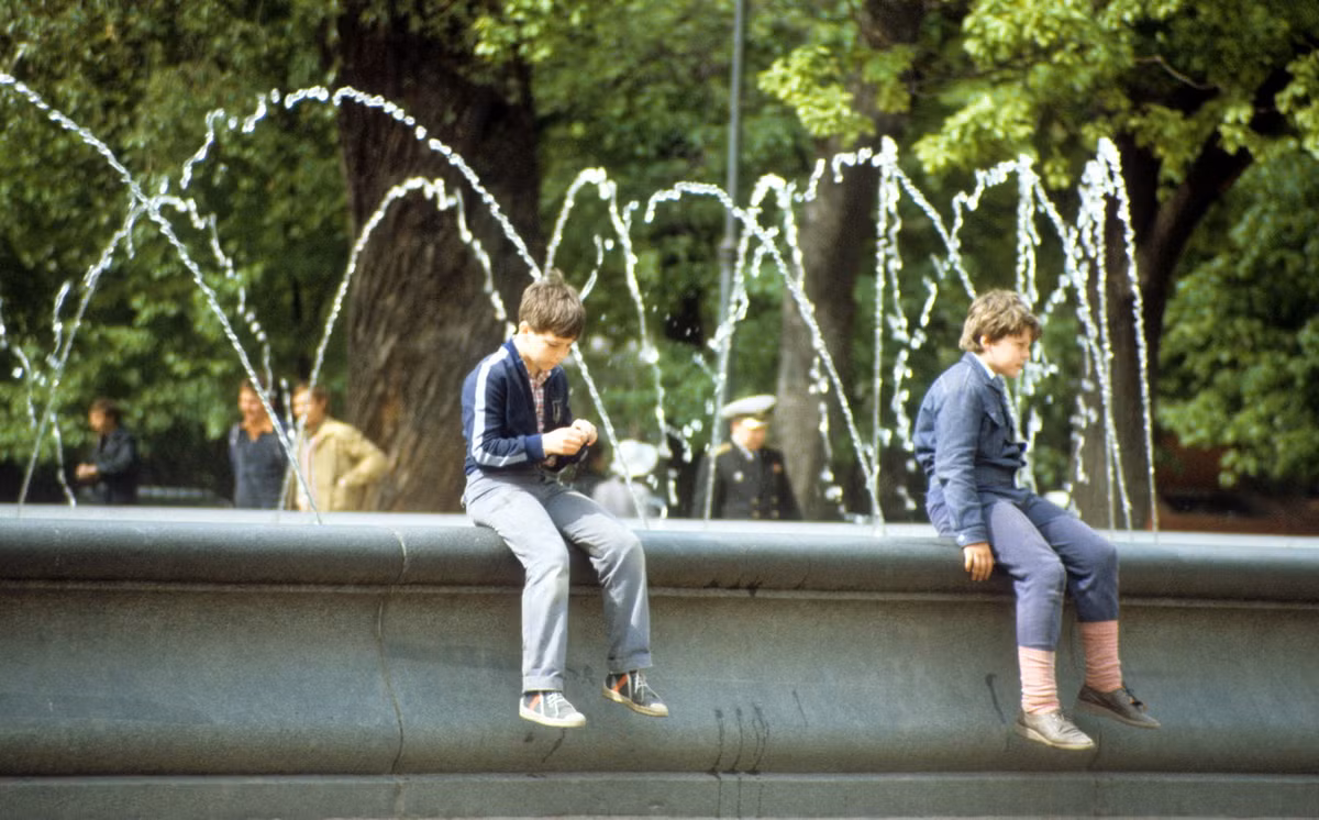 Hai cậu bé ngồi trên đài phun nước tại một công viên.