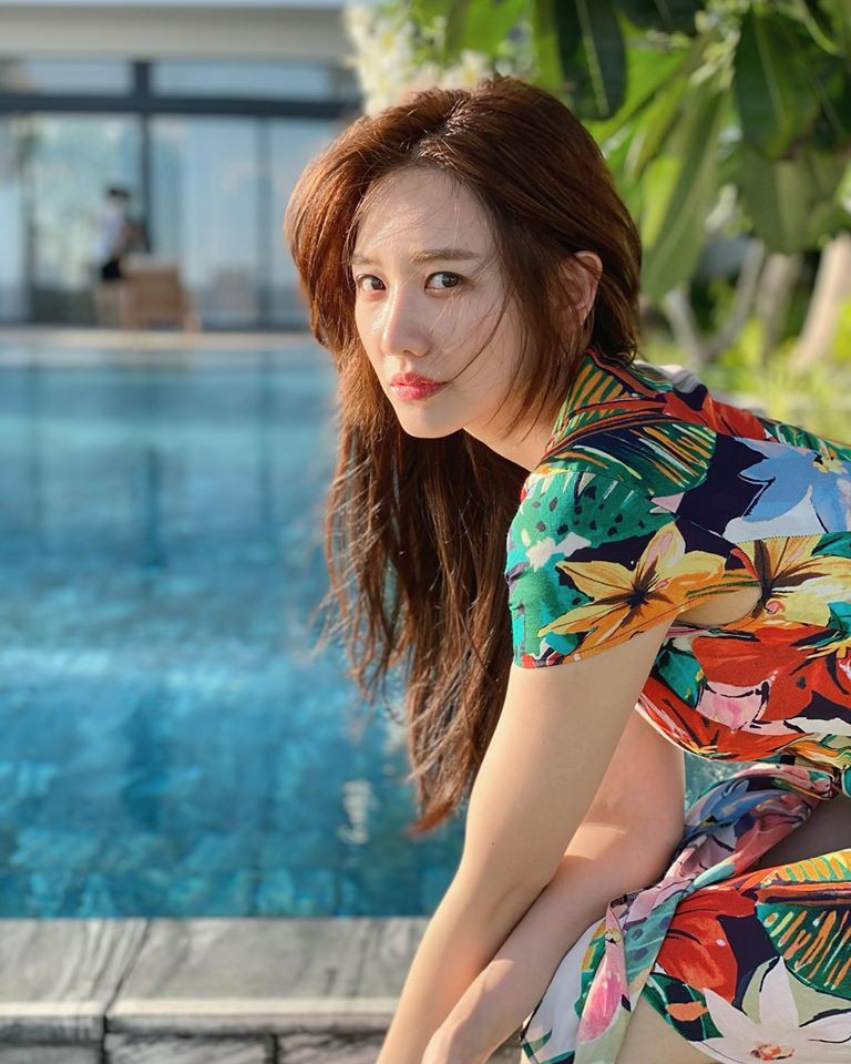 Cô diện chiếc váy hoa sặc sỡ với phong cách mùa hè, mái tóc buông xõa không tạo kiểu.