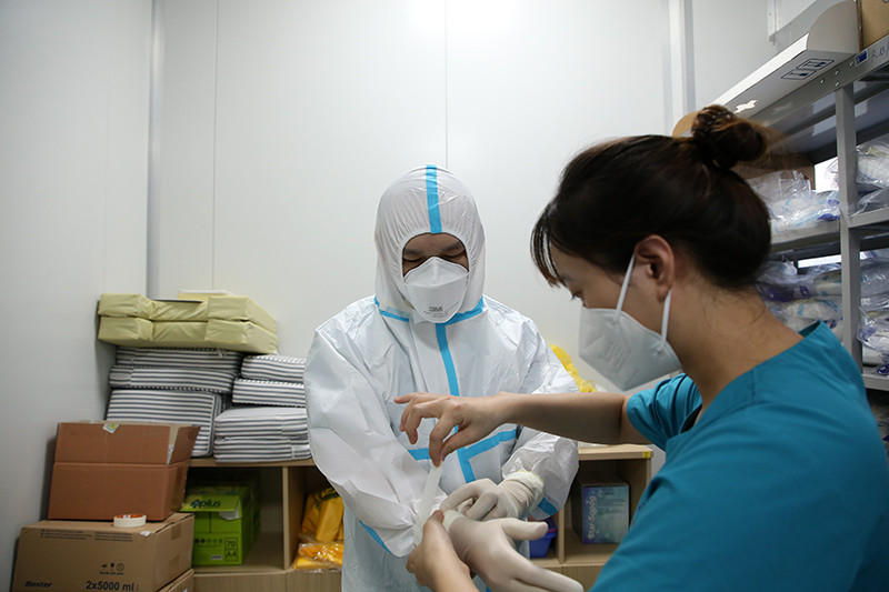 Các y bác sĩ giúp đỡ nhau mặc đồ bảo hộ trước khi vào khu điều trị bệnh nhân nhiễm Covid-19 nặng. 