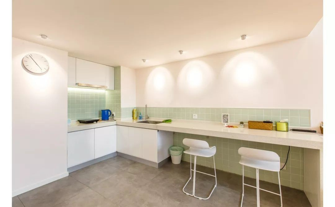 Bước vào không gian chính là khu vực bếp được bố trí sát tường. Góc bếp với hệ thống tủ trên và dưới được thiết kế gọn xinh, đủ để mọi người thoải mái sử dụng với chức năng sinh hoạt thường ngày như chuẩn bị đồ ăn, nấu nướng, pha trà, cà phê….Phòng bếp được bố trí siêu đơn giản, ánh sáng đóng vai trò vừa để chiếu sáng vừa để tăng thêm điểm nhấn ấn tượng cho khoảng gạch xanh ốp tường.