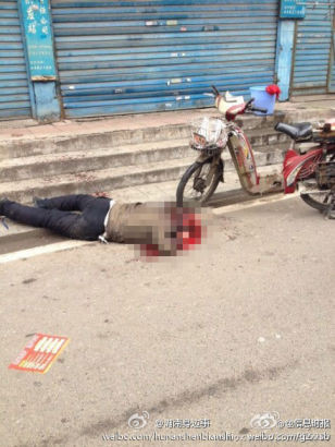 Xác một nạn nhân nằm giữa vũng máu trên vỉa hè.