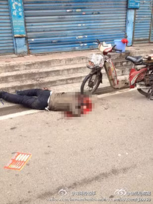 Xác một nạn nhân nằm giữa vũng máu trên vỉa hè.