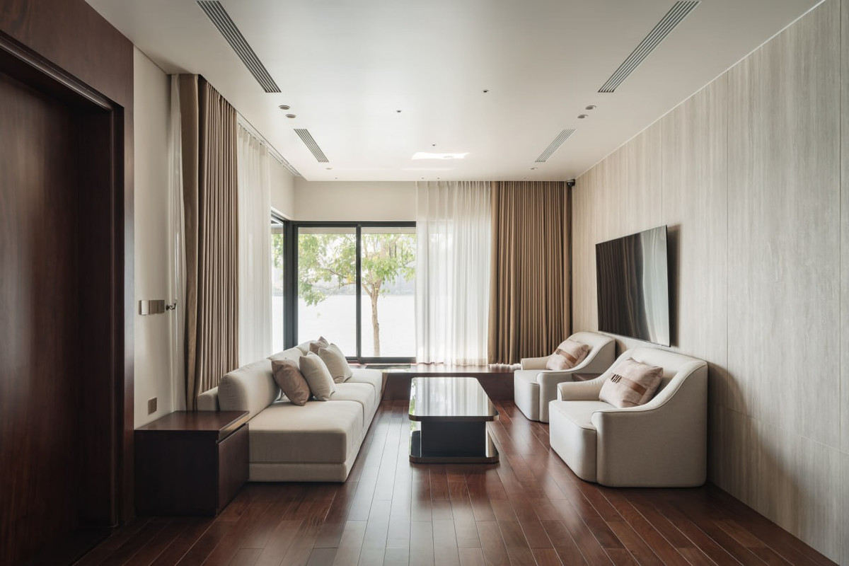 Nếu nhìn lướt qua tổng thể một căn nhà có mặt tiền rộng như thế này, ai cũng nghĩ rằng phòng khách sẽ rất to và hoành tráng, nhưng căn nhà này thì ngược lại. Không gian phòng khách với diện tích khiêm tốn và thiên về sự thư giãn, tận hưởng khoảng không gian trước nhà.