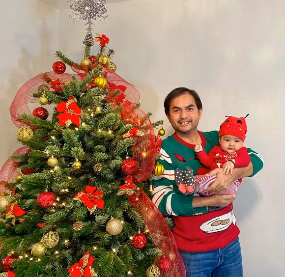 Đức Tiến chụp ảnh cùng con bên cây thông.