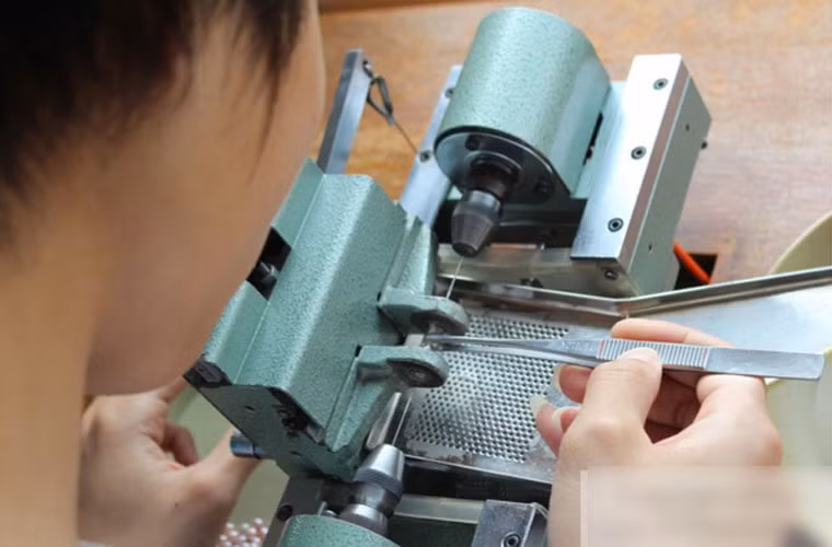 Đây là máy khoan lỗ ngọc trai độc quyền của nhà máy Yakushi. Rất nhiều công ty khác có chiếc máy khoan ngọc trai nhưng đây là chiếc máy đặc biệt do nhà máy tự phát minh, có thể khoan lỗ ngọc trai chính xác hơn và nhanh hơn nhiều so với khi làm bằng tay.