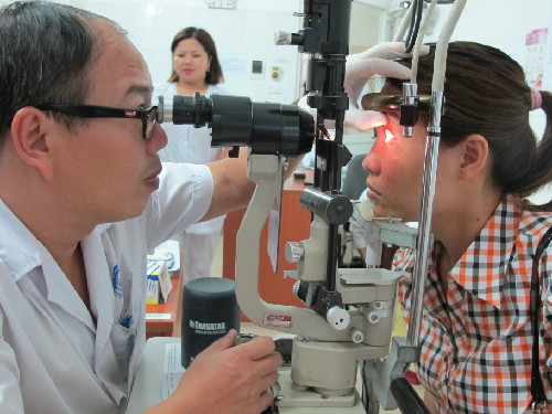 Bác sĩ Hoàng Cương đang khám bệnh đau mắt đỏ cho bệnh nhân.