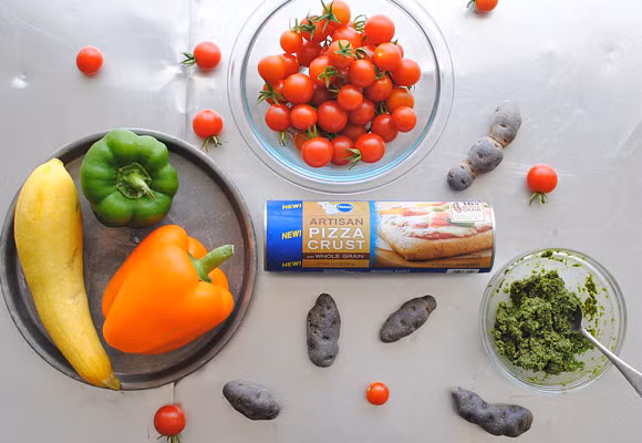 Nguyên liệu làm bánh pizza cầu vồng gồm có vỏ bánh, nước sốt pizza, ớt chuông các màu, cà chua bi, bí vàng, cà tím, dầu oliu, gia vị làm pizza, phô mai, hạt tiêu, sốt pesto.