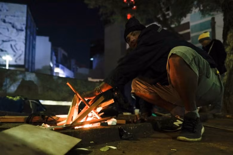 Một người đàn ông sưởi ấm bên đống lửa tại đường phố Sao Paulo.