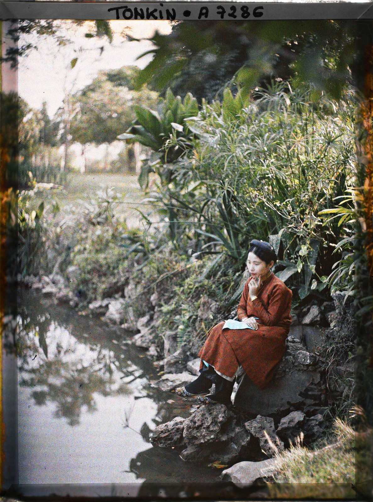 Thiếu nữ ngồi thẩn thơ bên hồ nước công viên.