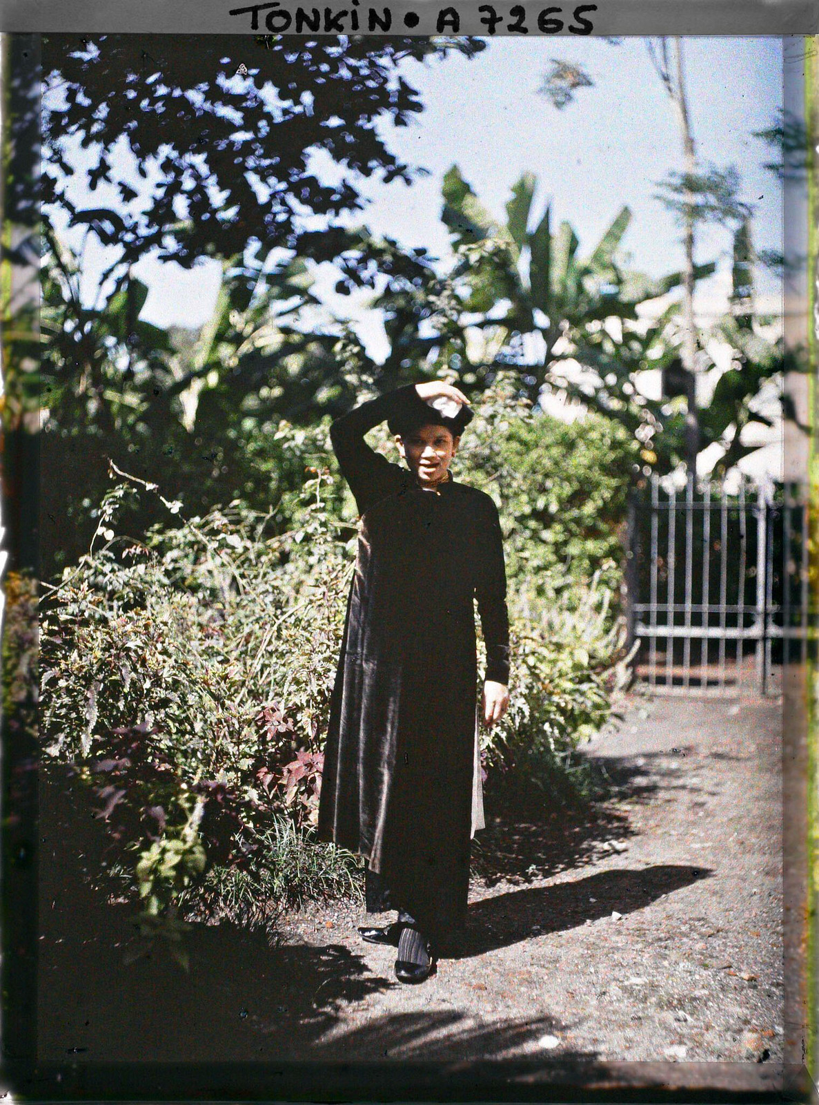 Người phụ nữ lấy tay che nắng khi đứng trong khu vườn.