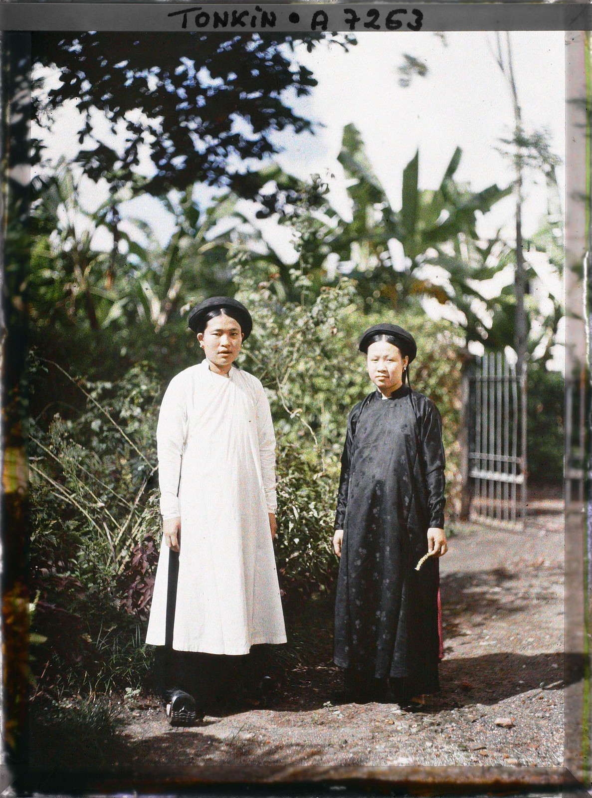 Hai cô mặc áo dài màu sắc tương phản, một đen, một trắng.