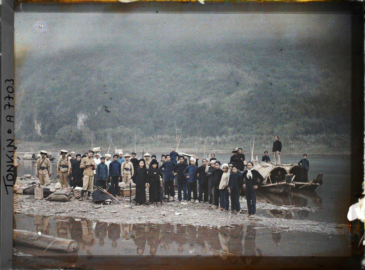 Người dân, du khách và binh lính bản xứ đứng trên bờ sông Đà ở Chợ Bờ.