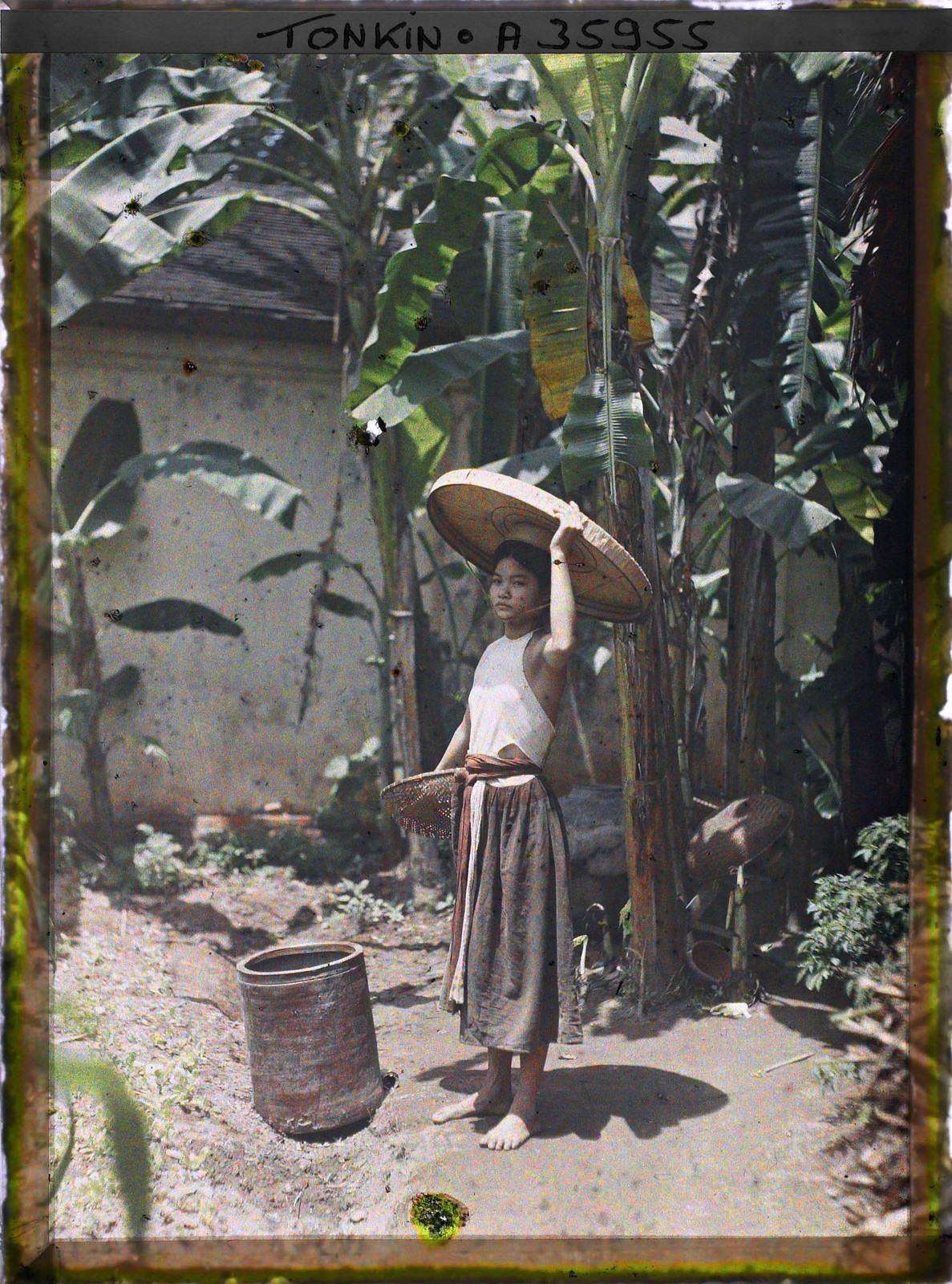 Một tay cầm rổ, một tay đỡ nón quai thao.