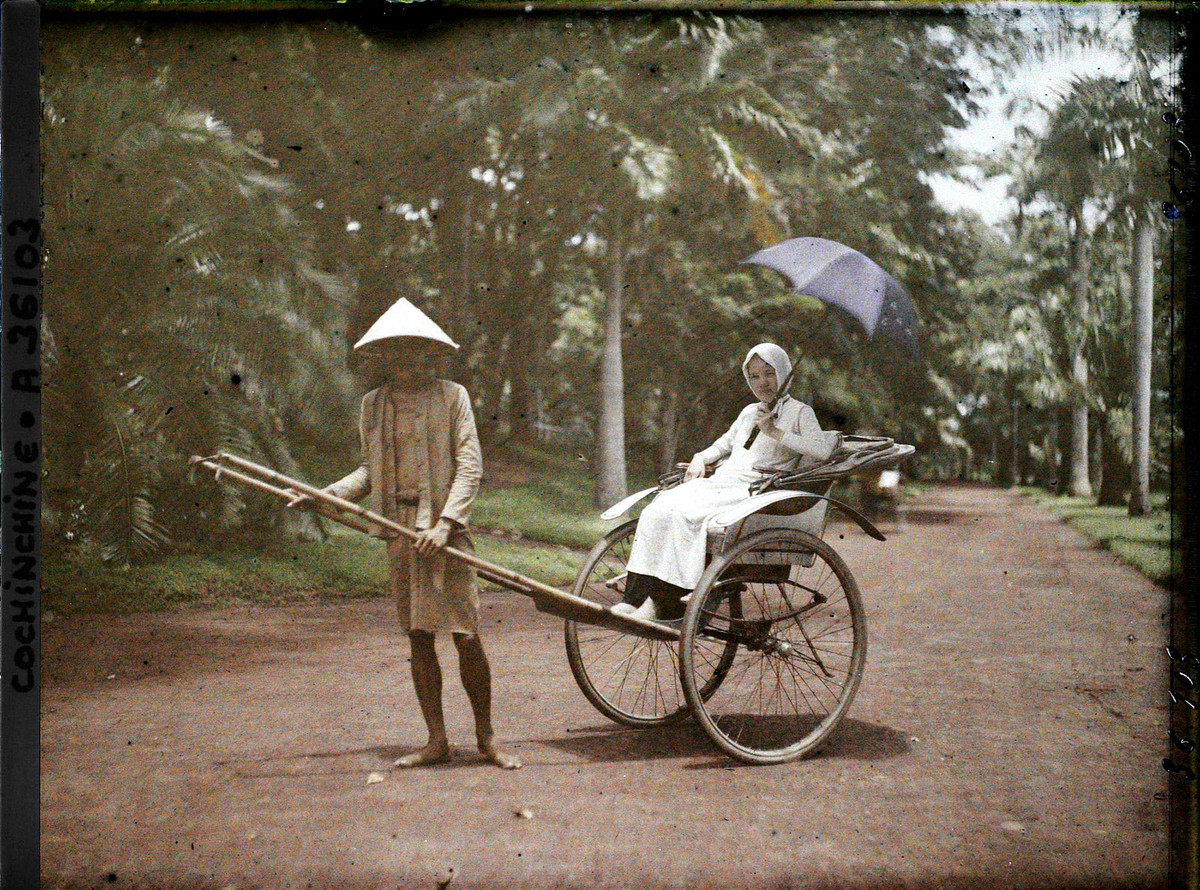 Người phụ nữ trẻ cầm ô, ngồi trên xe tay ở Thảo Cầm Viên Sài Gòn năm 1921.