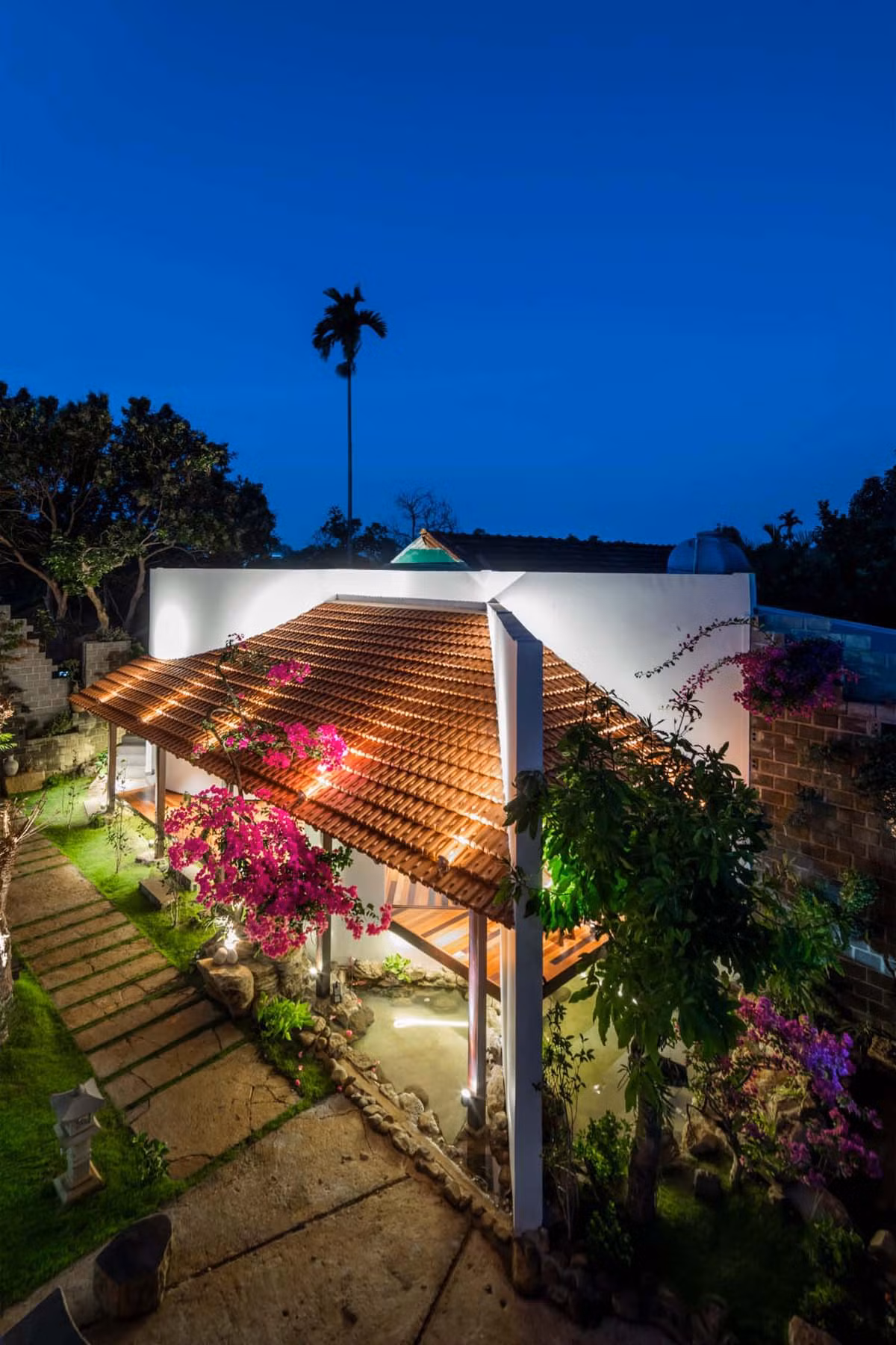 Công trình hầu như không có “mặt tiền” theo kiểu thông thường mà sau mảng tường vát chéo khi qua cổng rào, một “mặt cắt” bộc lộ cấu trúc thể hiện đúng bản chất của nơi chốn. Lối đi xanh mướt một màu dẫn vào ngôi nhà.