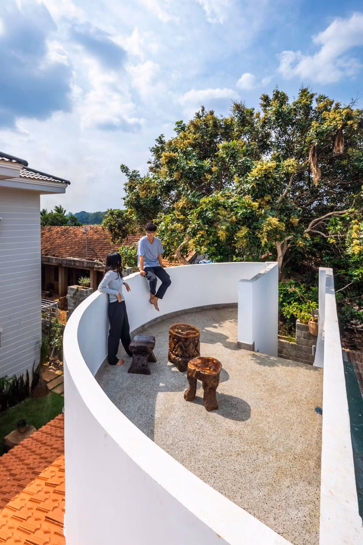 Trên mái có 1 sân thượng cong hình con thuyền, tạo sự mềm mại, tương phản với mái hiên trải dài của công trình. Gia chủ muốn thiết kế sân thượng dùng để ủ và phơi nắng hũ đậu, tuy nhiên khi hoàn thành, nơi đây trở thành địa điểm đa năng, có thể dùng cho việc thư giãn của mọi thành viên trong gia đình.