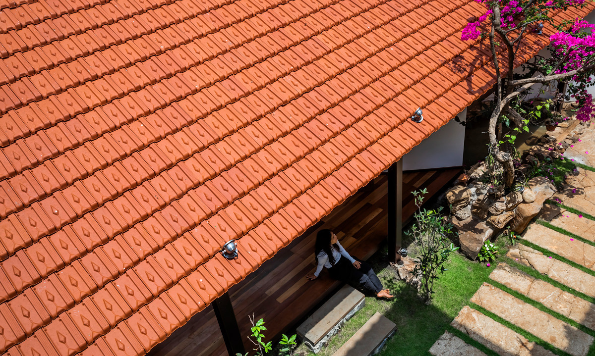 Các vật liệu cũ và vật liệu hiện đại có sự đan xen hài hòa. Phía trên mái còn có một hệ kính lấy sáng. Hàng hiên mái ngói đỏ là thiết kế quen thuộc của nhà nông thôn Việt Nam trước đây. Phần rìa mái hiên đủ tầm với tay nếu muốn chạm vào ngói. Thiết kế này cũng tránh việc bị mưa tạt vào không gian phía trong. Hệ mái được phát triển dài theo khu đất, song song và mở về phía gian nhà chính của gia chủ nhằm tăng sự kết nối giữa hai không gian.