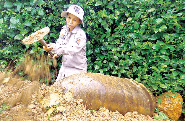 Chị Hoàng Thị Hải Lý - một trong tám kỹ thuật viên nữ của đội rà bom mìn sót lại sau chiến tranh tại Quảng Trị do Vương quốc Anh tài trợ. Các chị bảo đây là nghề săn thần chết! Trong ảnh: chị Lý đang đào một quả bom khổng lồ.
