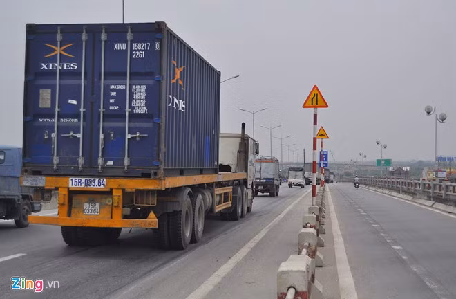 Biển báo làn đường bị thu hẹp bên trái và một biển thông báo làn đường mấp mô ở phía trước được cắm trên cầu Thanh Trì.