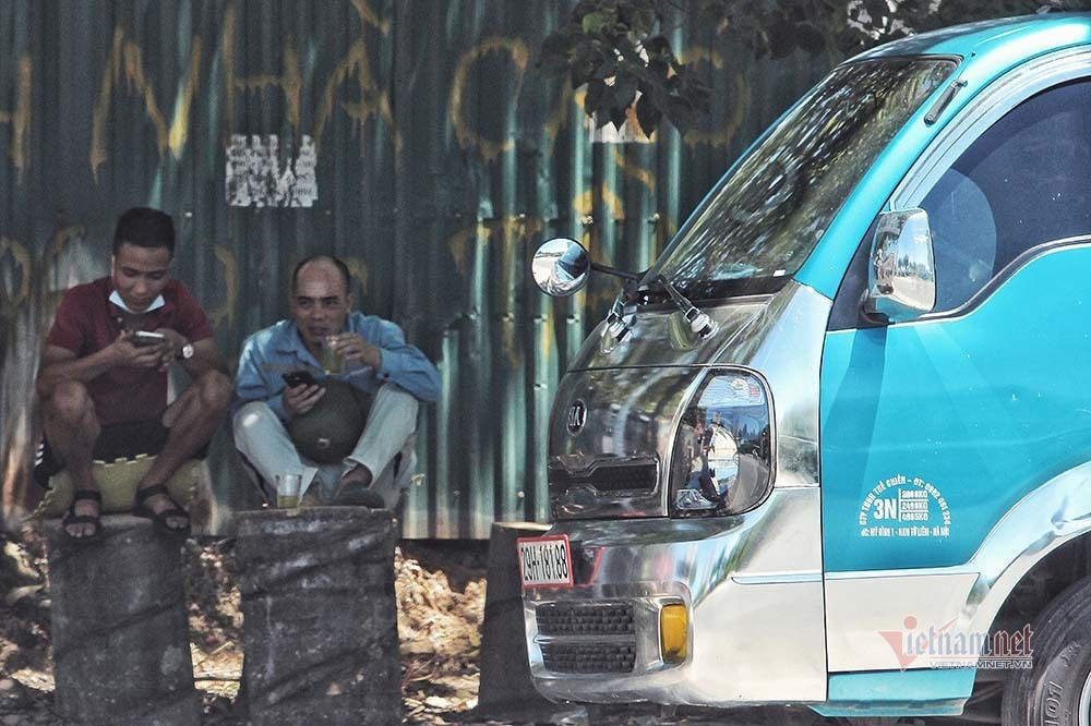 Để chống chọi với cái nắng cháy da, nhiều người chọn cách mặc nhiều áo và mang theo đồ uống mát lạnh để giải nhiệt. Ảnh: Phút giải lao dưới bóng cây của lái xe chở hàng