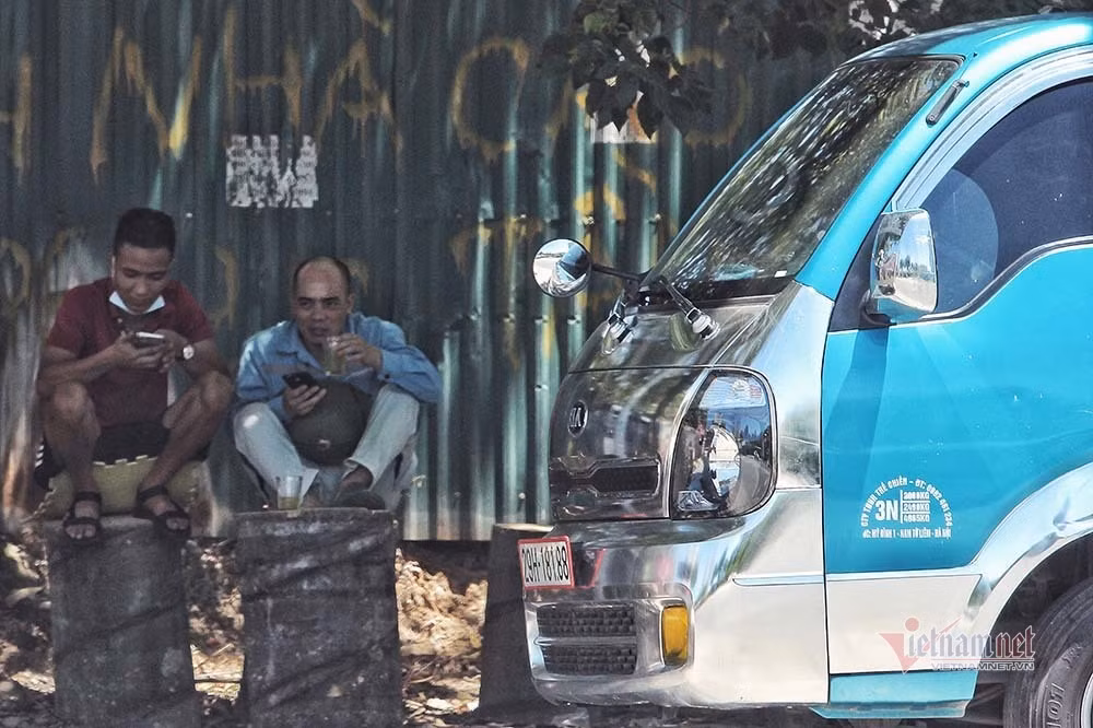 Để chống chọi với cái nắng cháy da, nhiều người chọn cách mặc nhiều áo và mang theo đồ uống mát lạnh để giải nhiệt. Ảnh: Phút giải lao dưới bóng cây của lái xe chở hàng
