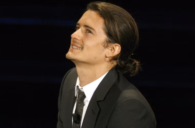 Orlando Bloom trông "nữ tính" hơn với kiểu tóc dài, buộc túm phía sau.