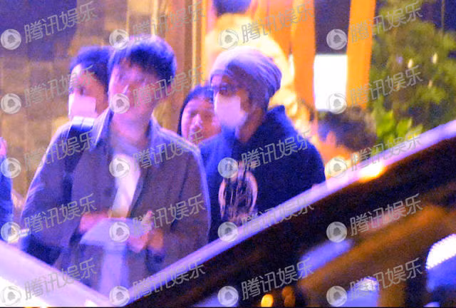 Hai ngôi sao mặc quần áo đôi tối màu, mặt bịt kín khẩu trang, và có ý tránh né ống kính máy ảnh.