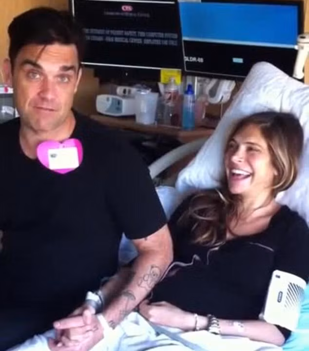 Hai vợ chồng ngôi sao pop nắm chặt tay nhau, tươi cười sau khi vợ Robbie vừa hạ sinh cậu con trai thứ 2 hôm 27/10.