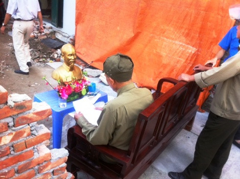 Một người dân lớn tuổi dùng ghế chắn ngang lối đi chung, phản đôi việc xây dựng.