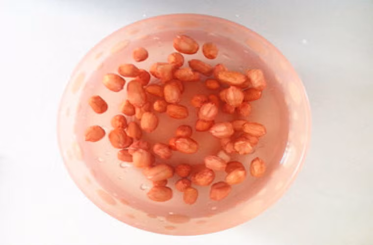 Dùng nước nóng ngâm lạc khoảng 15 phút.