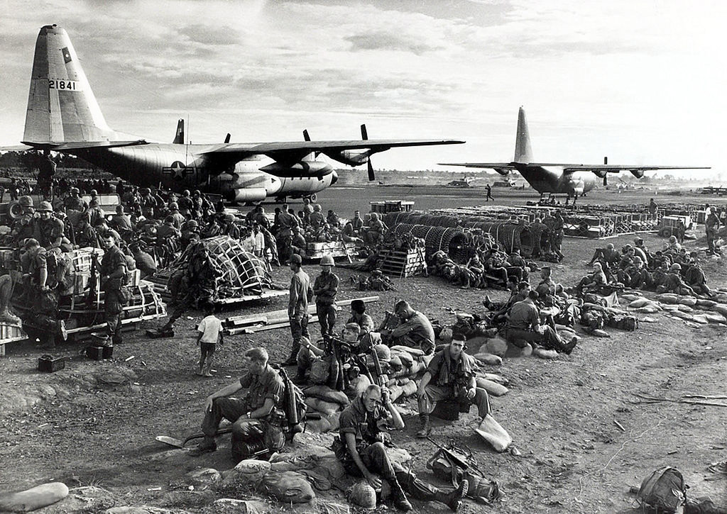 Binh sĩ của Sư đoàn Bộ binh số 1 Mỹ ngồi trên đường băng cùng hành lý trước khi được chở ra trận địa bằng máy bay C-130.