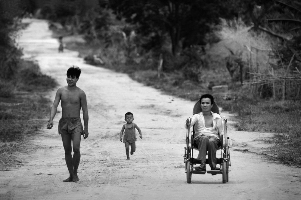Một cựu chiến bịnh bị chấn thương cột sống do mảnh bom trong thời gian hoạt động trên đường Trường Sơn ngồi xe lăn trên con đường mòn của ngôi làng ở A Lưới, Huế.