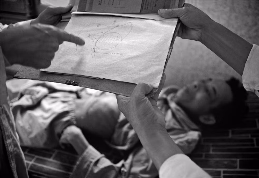 Bác sĩ Tôn Thất Tùng cầm hình vẽ lá gan minh họa bệnh tình của người thương binh.