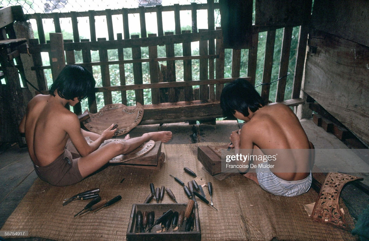 Hai người thợ chạm khắc gỗ tại xưởng mộc.