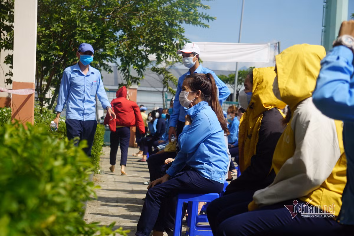 Được biết, đến 11h cùng ngày, công ty này đã ghi nhận 15 ca dương tính nCoV. (Công nhân dùng áo khoác che nắng chờ đến lượt lấy mẫu)
