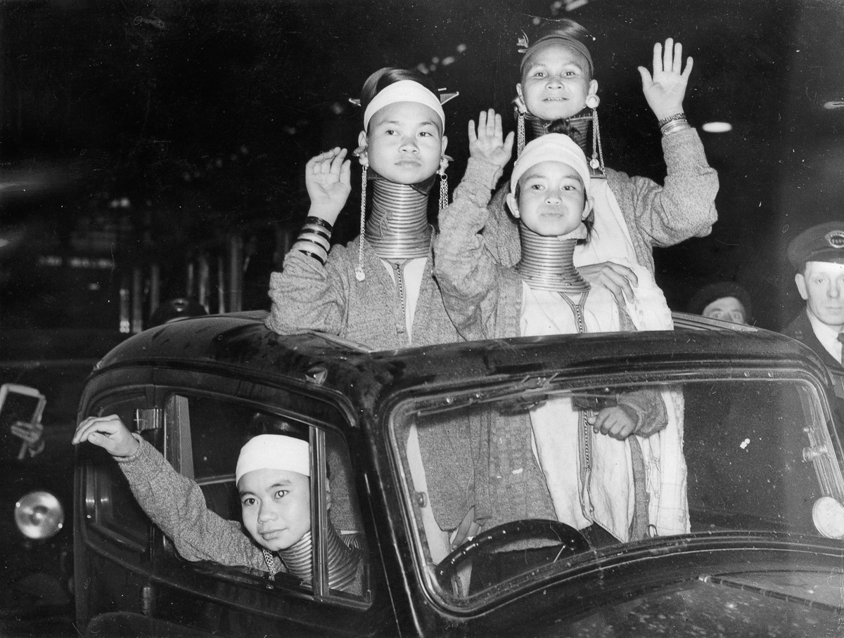 Các phụ nữ Padaung vẫy tay chào người dân London khi họ được đưa ra từ nha ga. Vào thập niên 1930, một số phụ nữ Padaung đã được đưa từ Miến Điện - khi đó là thuộc địa của Anh - sang London để phục vụ cho các gánh xiếc tại thành phố này.