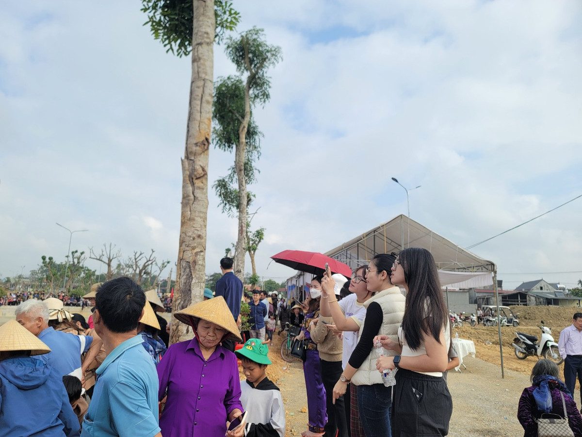 Nhiều bạn trẻ đứng trên bờ quay phim, chụp ảnh lễ hội bắt cá hồ Cầu Bè.